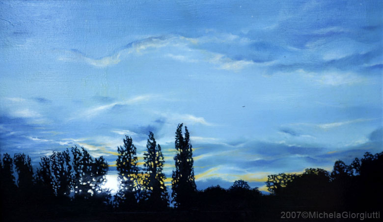 Cielo blu al tramonto con riflessi gialli e silhouette di alberi